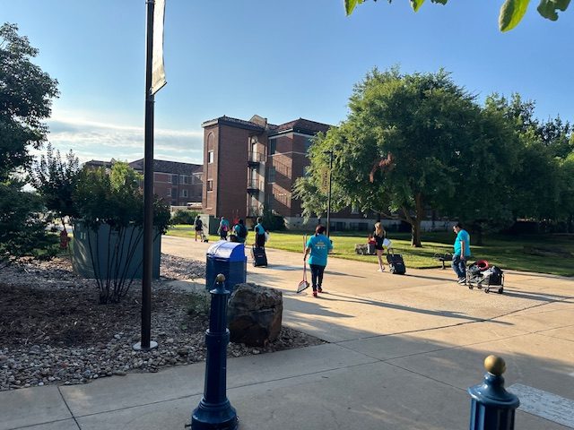 CHA crew in teal shirts working along a campus walkway