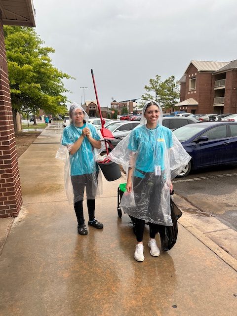 Two CHA team members in rain ponchos with cleaning cart