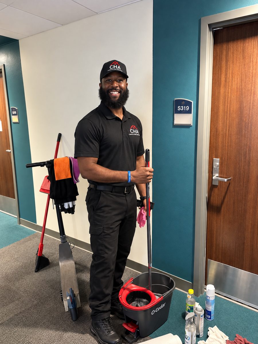 CHA team member in uniform with mop bucket and supplies in an office hallway